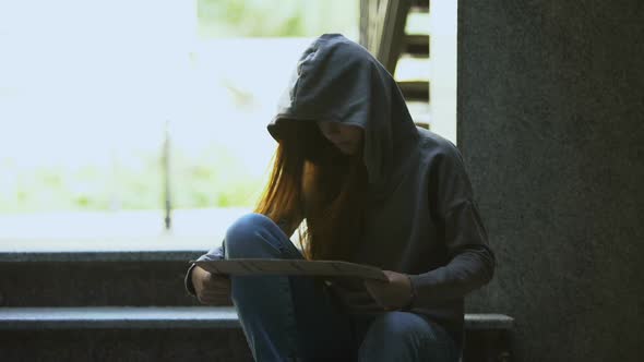 Homeless Teenage Girl in Hoodie Showing Help Sign on Stairs, Social Insecurity alt