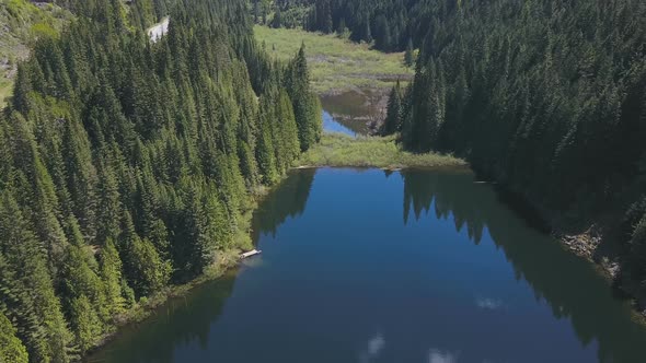 Aerial Drone Of A Lake And Valley With Reflections Of Evergreen Trees On A Mountain 2