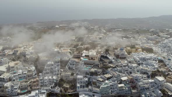 Aerial view over the clouds of traditional white houses on Santorini island. alt