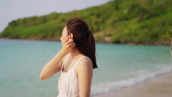 4K Asian man cover his wife with a blanket and hugging each other on the beach at summer sunset.