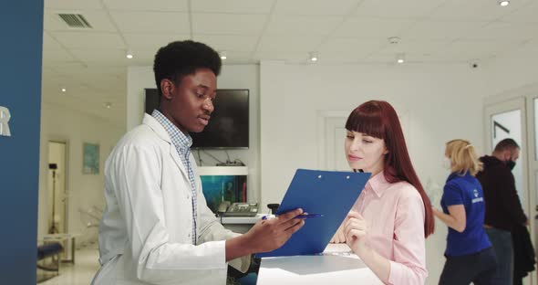 Doctors Meeting in Hospital Corridor Discussing Test Results on Tablet alt
