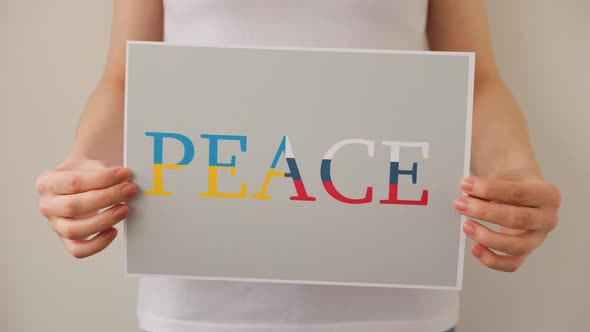 Close Up of a Protester Hands Holding Cardboard Banner with the Words Peace alt