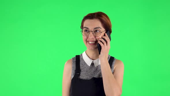 Portrait of Funny Girl in Round Glasses Is Talking for Mobile Phone. Green Screen alt