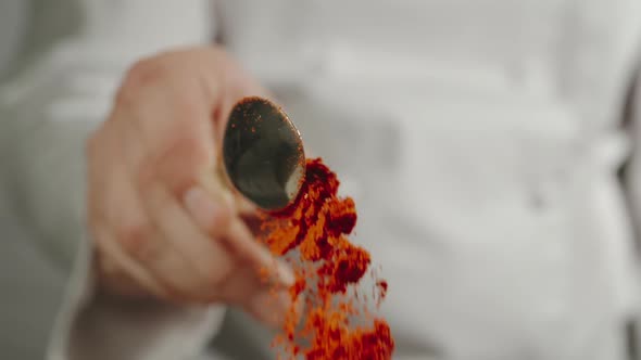 Chef Sprinkles Red Pepper Powder From A Spoon