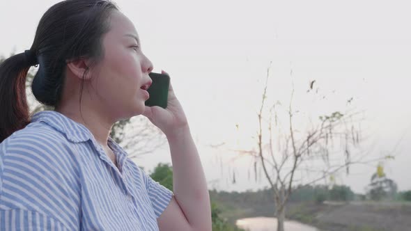 Asian short hair woman using smartphone answer the call to friend at outdoor alt