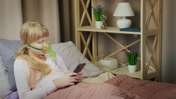 The Child Does Inhalation at Home Uses a Smartphone alt