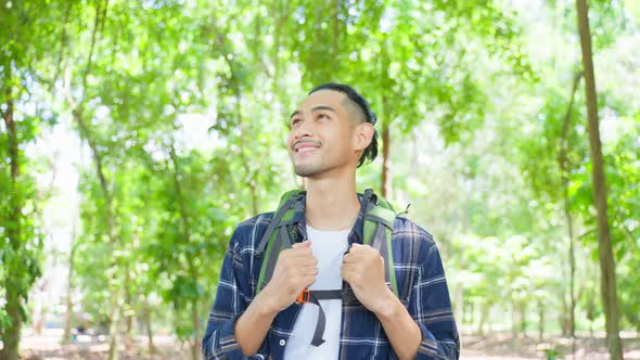 Asian young handsome male backpacker traveling alone in forest wild on holiday vacation. alt