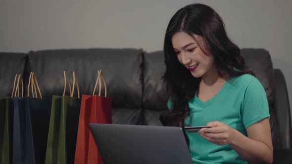 happy woman using laptop computer for online shopping with credit card in the living room