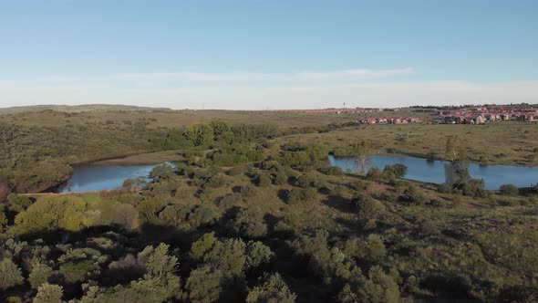 AERIAL Reverse Shot of a DAM in a Green Valley with Housing in the BACK alt