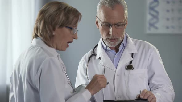 Doctors Having Discussion on Results, Woman Holding Tablet, Man With Notepad alt