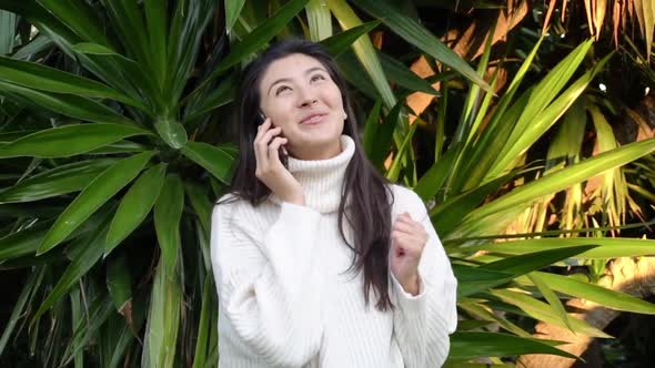Young Asian Woman Use the Phone with Earphones While Walking
