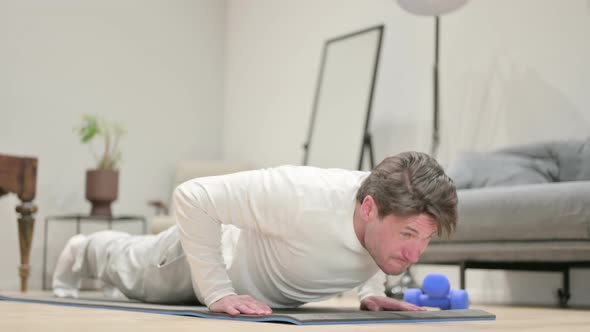 Tired Middle Aged Man Doing Pushups on Yoga Mat at Home alt