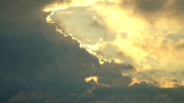 Thick natural clouds through which orange sunlight breaks through at dawn