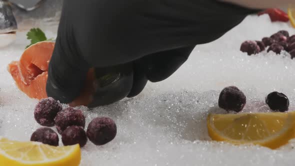 A Blackgloved Fishmonger Picks Up Salmon Steaks From a Snow Display Case alt