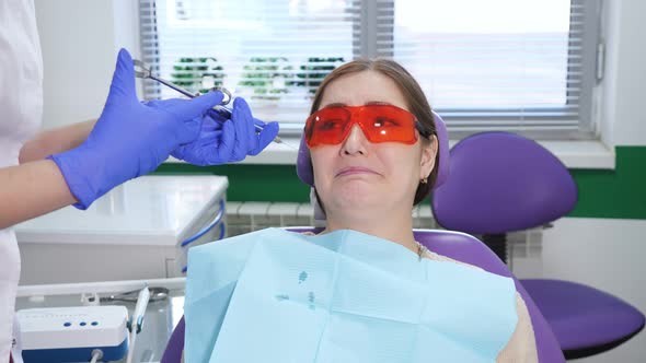 Portrait of Young Woman Afraid to Remove a Tooth Sitting in Dental Chair alt
