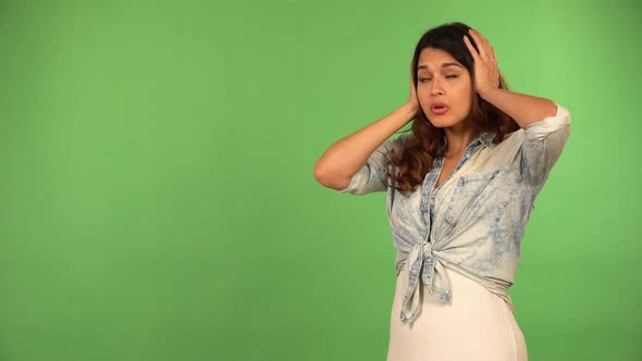 A Young Beautiful Caucasian Woman Hears a Loud Noise and Covers Her Ears  Green Screen Background