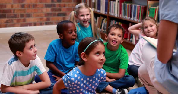 Pupils sitting listening to their teacher in the library alt
