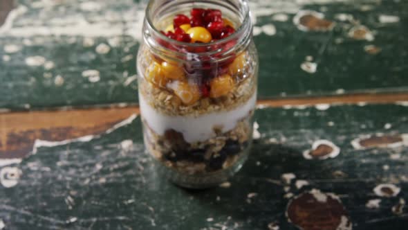 Yogurt with pomegranates and golden berries in glass jar 4k alt