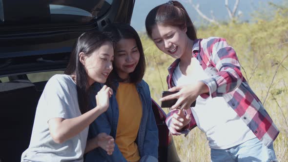 Group of a young teen Asian women checking photos on the mobile phone with friends camping