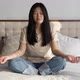Beautiful Asian Woman in Casual Clothes Practicing Yoga Lesson Breathing Meditation on the Bed - VideoHive Item for Sale