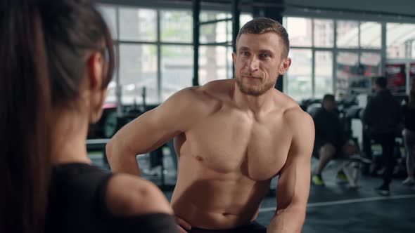 Bodybuilder communicates with beautiful female athletes in the gym, flirts alt