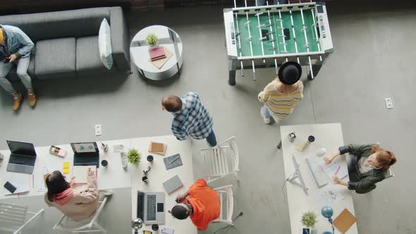 Top View of Modern Business Men and Women Working and Relaxing Playing Table Soccer in Office alt