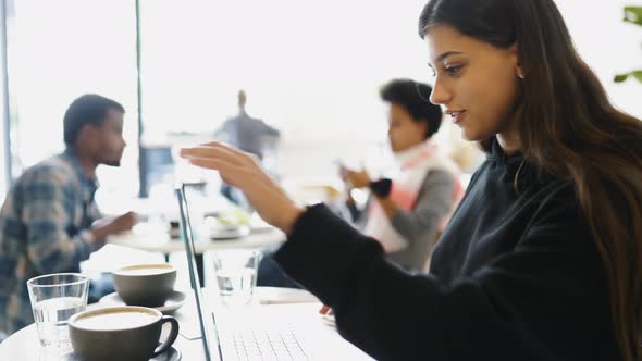 Female Student Using Netbook While Sitting in Cafe alt
