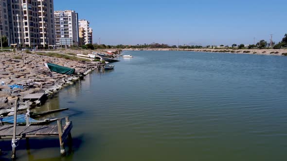 The Segura River flows to the ocean on the coast of Spain with old and sunken boats along the shore alt