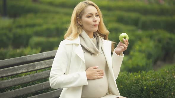Happy Expecting Woman Biting Green Apple, Stroking Belly, Maternity Health Care alt