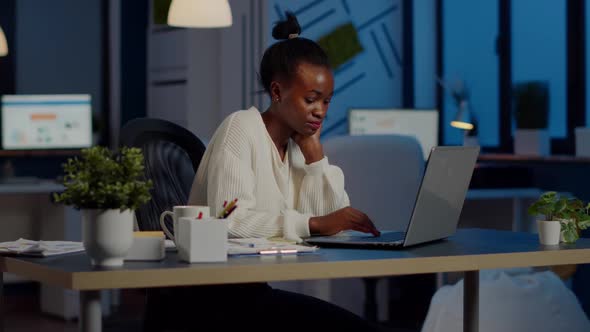 Overworked African Manager Woman Massaging Head While Sitting at Workplace alt