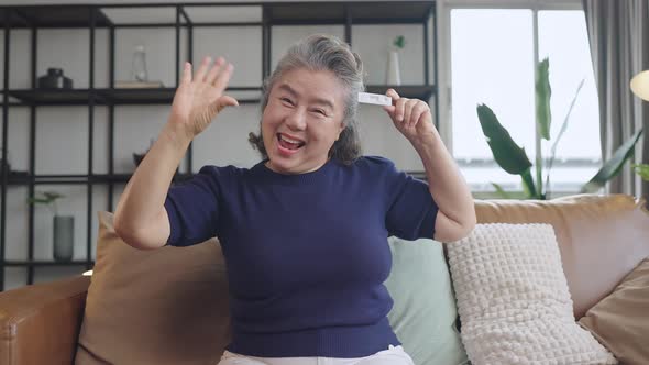 old senior retired asian female hand hold gesture and show covid-19 rapid test kit alt