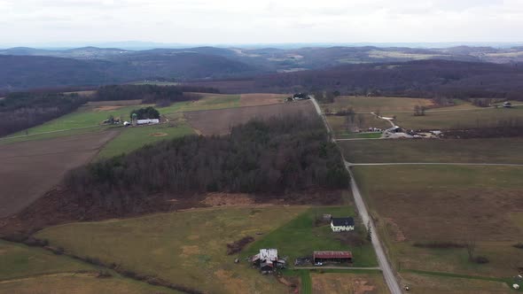Flying over landscape in Pennsylvania covered in fall colors with small farms here and there alt