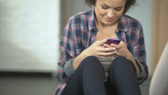 Smiling Young Woman Chats with Friends on Phone, Social Media Applications alt