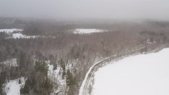 Aerial flying high above Winter forestry view with thick snowfall alt