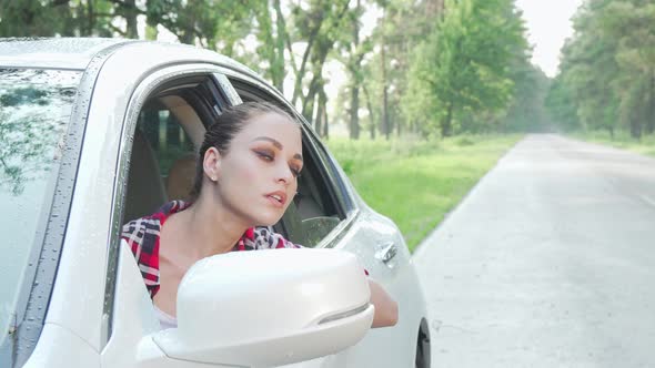 Young Woman Sitting in Her Car Looking Around on Countryside Road alt