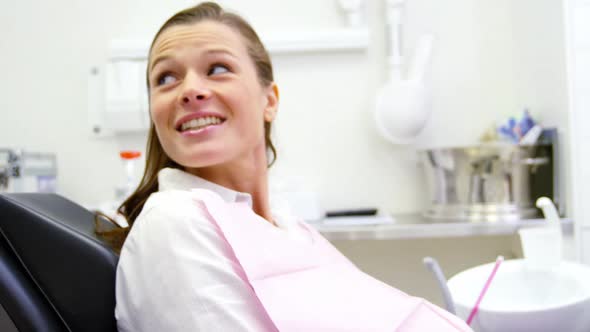 Smiling dentist talking to female patient alt
