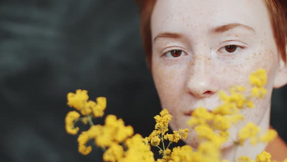 Young Redhead Woman Posing for Camera with Yellow Wildflowers alt