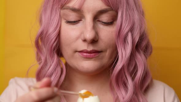 Closeup of Attractive Young Woman Enjoying Eating Jammed Chicken Egg on Yellow Stele Background