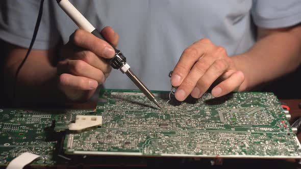 A Soldering Iron In His Hands. Technical Electronics Soldering motherboard engineer at work alt