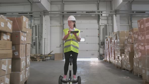 Female manager or storekeeper at logistics warehouse checks goods in cardboard boxes for shipment alt