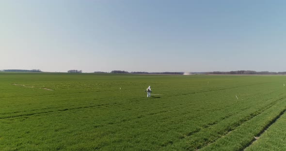 Agricultural Researcher Spraying Filed with Herbicides or Pesticides alt