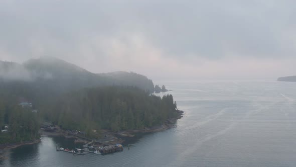 Aerial View of a small secluded town on the Pacific Ocean Coast during a cloudy summer sunrise. Take alt
