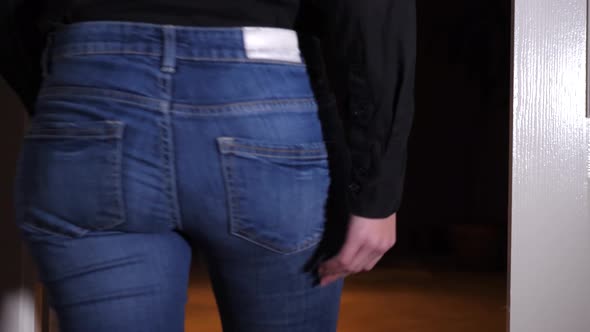 Woman walks and immediately stops because of stabbing anal pain, she puts hands on her buttocks alt