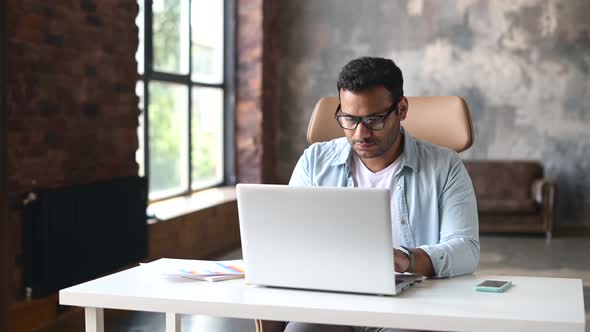 Intelligent Indian Businessman Using a Laptop in the Office alt