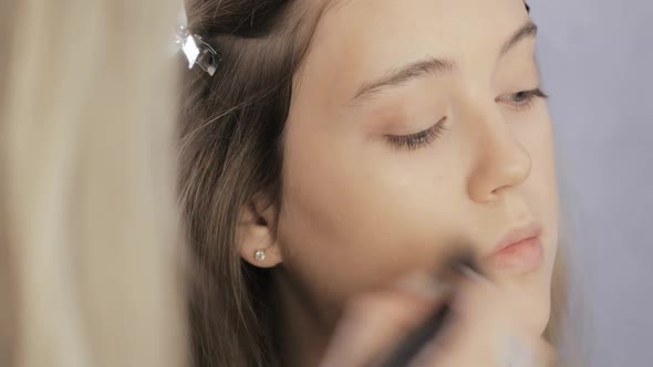 Makeup Artist Is Applying Blush Bronzer Using Brush To Young Model Cheekbone