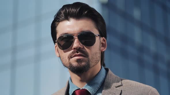 Portrait of Young Handsome Successfull Bussinessman Wearing a Suit and Sunglasses Standing Near alt