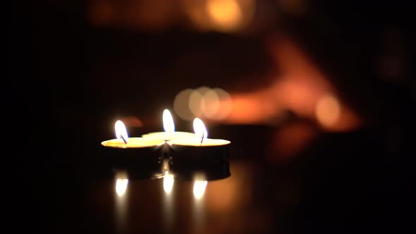 three candles on a black background with a fireplace flame.