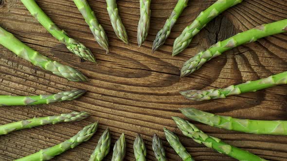 Raw garden asparagus stems. Fresh green spring vegetables on wooden background. 