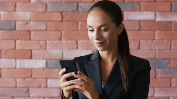 Smiling Businesswoman with Ponytail Using Smartphone alt