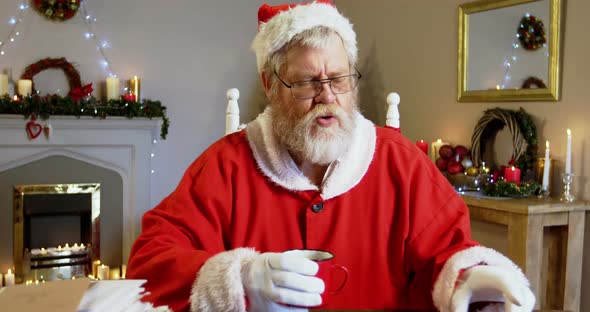 Santa claus relaxing on chair and having coffee alt